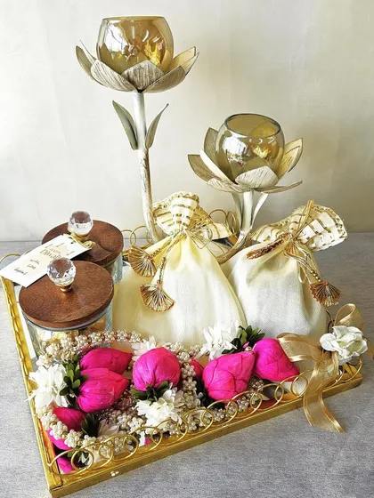 A beautiful blend of tradition and modern style, this hamper features lotus candle holders and jars of treats on a golden tray. The vibrant pink floral decorations add a pop of color and festive cheer.