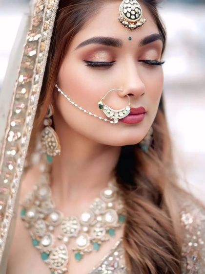 A close-up of the bridal look with the pastel green lehenga. The jewellery features a matching nath and maang tikka with mint green accents.
