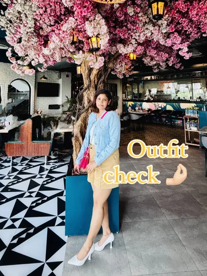 A full-length shot of my birthday outfit under a beautiful cherry blossom tree installation, showing the complete look with white heels.