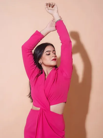 An expressive pose that showcases the vibrant color of the dress. The makeup is kept classic to balance the boldness of the outfit.