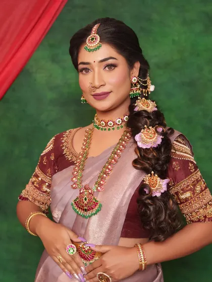 I absolutely adore working with unique color palettes. This elegant Muhurtham look features soft, rosy eyeshadow and a mauve lip to beautifully complement the lavender saree, showing how we can customize traditional looks to match your personal style.