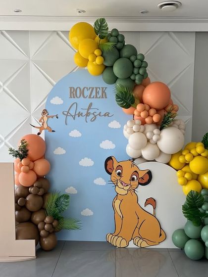 A wide view of the Lion King first birthday setup against a modern textured wall.