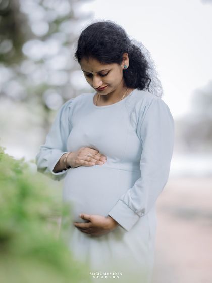 A contemplative solo portrait. The mother-to-be looks down at her belly, capturing a personal and reflective moment during her pregnancy.