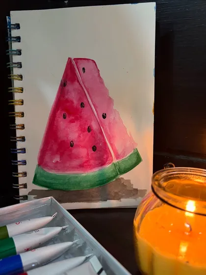 A watercolor painting of a slice of watermelon, done in my sketchbook by candlelight.
