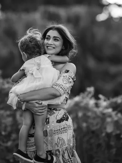 A tender moment between actress Shriya Saran and her daughter Radha, captured in black and white. This choice emphasizes the emotional connection and the pure joy in their embrace, creating a timeless image of a mother's love.