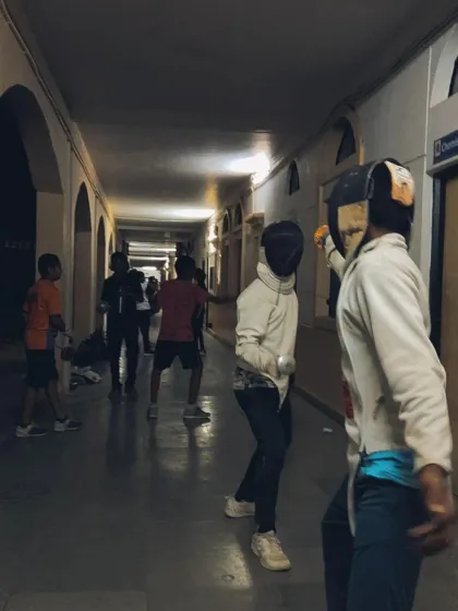 Two fencers spar while others observe in the background. Every moment at the camp is a learning opportunity, whether you are fencing or watching.
