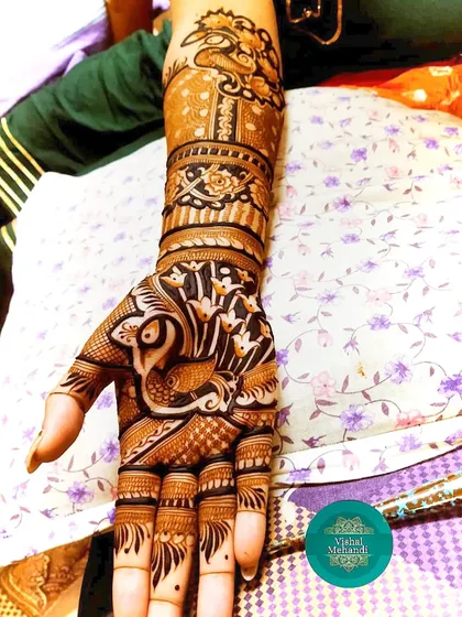 A classic design featuring a prominent peacock on the palm and another on the forearm, surrounded by delicate floral patterns.
