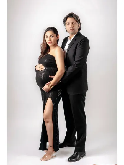 A formal and poised studio portrait of an expecting couple. Their elegant attire and confident pose create a timeless and sophisticated image of their family-to-be.