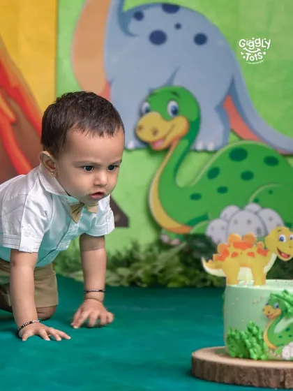 What's a birthday without a little bit of cake chaos? This curious little explorer is having a roaring good time with his dinosaur-themed cake smash.