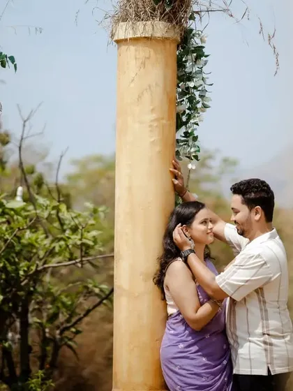 A beautiful, romantic moment between a couple during their pre-wedding shoot, set against rustic pillars and nature.