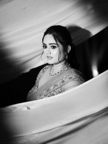 A timeless black and white bridal portrait. The soft fabric and dramatic lighting create a classic, cinematic feel, focusing on the bride's contemplative expression.