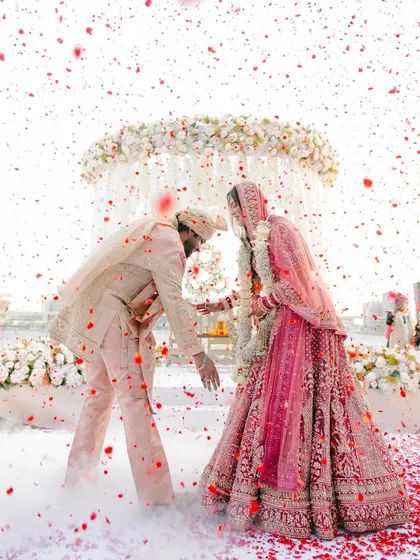 A whirlwind of love and petals. I styled this moment to feel like a dream, with a custom-coordinated pastel palette for the couple's outfits and a cloud of smoke to create an ethereal, romantic atmosphere for their varmala ceremony.