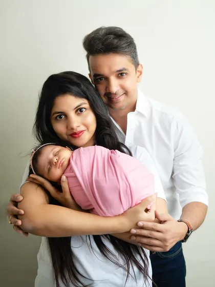 A beautiful family portrait showcasing the love that fills the room. The father's arm wrapped around his wife and new baby creates a feeling of warmth and protection.