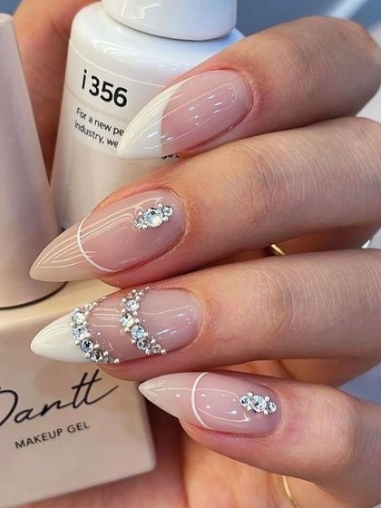 Nail inspiration for festive nails, featuring a white and nude base with intricate rhinestone patterns.