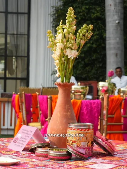 A beautiful centerpiece combining fresh tuberoses in a terracotta vase with traditional Indian favor boxes.