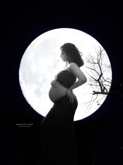 A powerful silhouette of the mother-to-be against a full moon. This dramatic, high-contrast black and white shot is both artistic and symbolic.