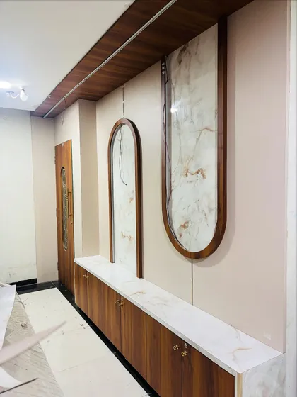 A custom foyer unit under construction, featuring a long wooden cabinet with a marble top and decorative marble panels on the wall.