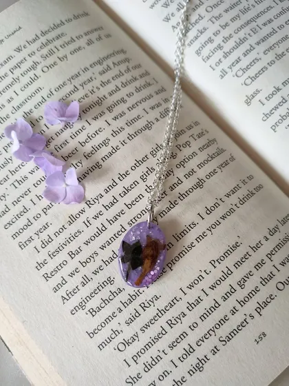 I also create wearable jewelry, like this custom resin pendant. It features a rare Neelakurinji flower preserved against a sparkling lavender background, hanging from a simple silver chain.