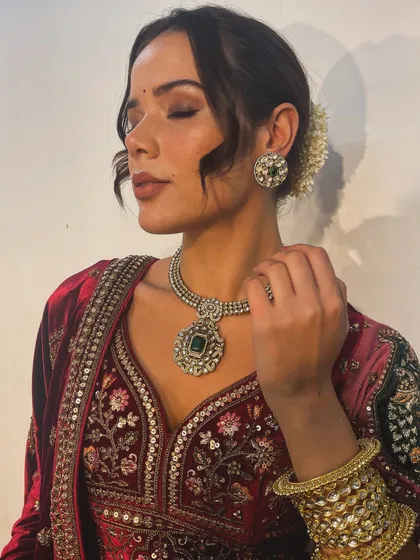 This image highlights the perfect pairing of a rich velvet lehenga with an emerald and polki diamond necklace. Coordinating the jewellery with the outfit's tones is key to a harmonious bridal look.
