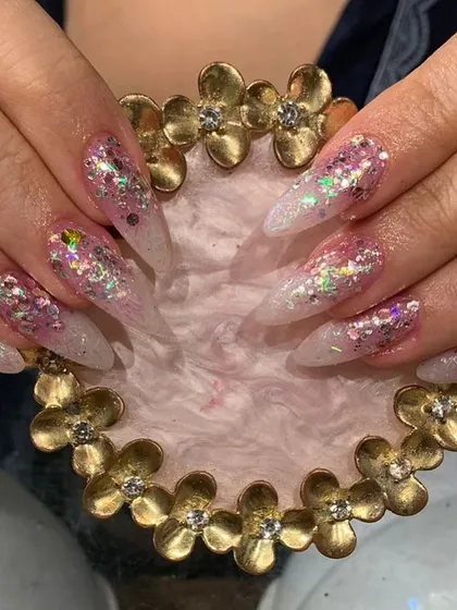 An explosive mix of holographic and iridescent chunky glitter over a sheer base on long stiletto nails.