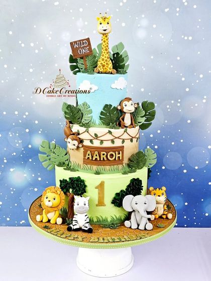 A three-tier "Wild One" jungle safari cake for Aaroh's first birthday. This cake is adorned with cute, handcrafted lions, zebras, elephants, and monkeys.