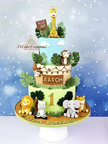 A three-tier "Wild One" jungle safari cake for Aaroh's first birthday. This cake is adorned with cute, handcrafted lions, zebras, elephants, and monkeys.