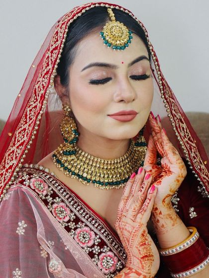 A serene pose with hands joined, showing the intricate mehndi and the beautiful makeup.