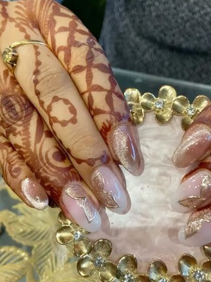 A detailed shot of the gold leaf nail art, showing how the metallic sheen complements the warm tones of the henna.