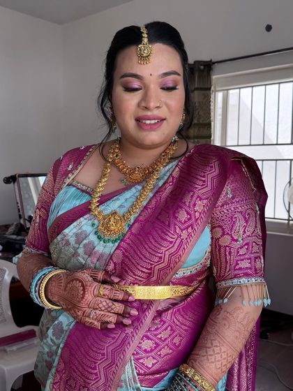 This image showcases the soft pink and mauve tones used for the eye makeup, which beautifully complements the colors in her silk saree. This is an unfiltered photo, showing the true texture of the skin.