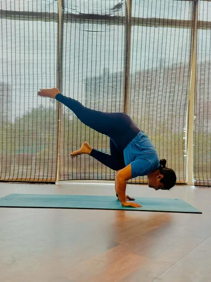 Here is a fantastic Eka Pada Bakasana, or one legged crow pose. This arm balance requires immense strength and control, and she is demonstrating it with grace.