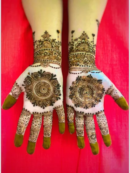 A beautiful and symmetrical design featuring intricate mandalas on the back of the hands. The delicate chains hanging from the wrist cuff add a touch of elegance.