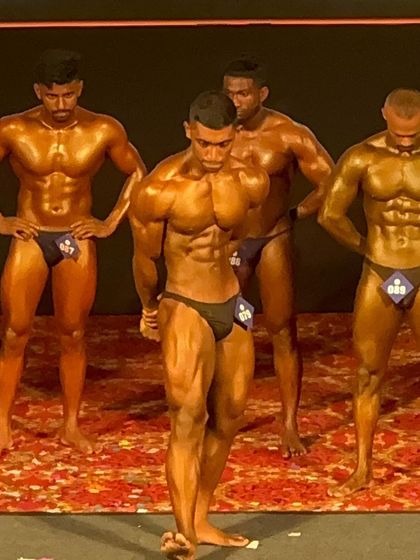 A classic physique pose on stage. Even though the category changed last minute, he brought his best-ever look and showcased it perfectly.