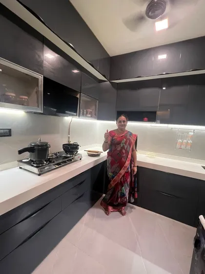 A happy client in her brand new, high-gloss grey modular kitchen. For us, a successful project is defined by this smile of satisfaction.