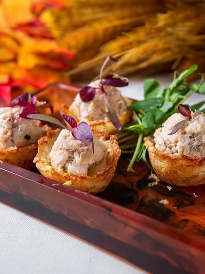 These bite-sized tartlets are filled with a savory chicken mousse and garnished with microgreens. They are a perfect example of how we craft joyful bites for any celebration.