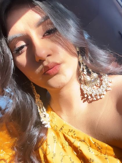 A close-up pouty selfie, giving a better look at the one-shoulder design of the yellow kurta and the beautiful chandelier earrings.