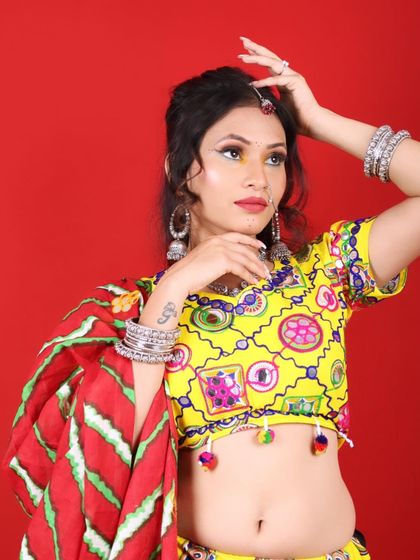 This model is ready for Garba night. The makeup is bright, with a pop of red on the lips and dramatic eyes, ensuring she stands out in the crowd and in photos.