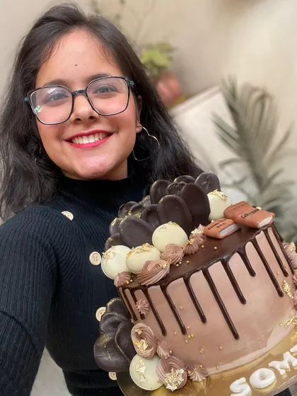 Here I am with one of my favorite creations, a custom chocolate drip cake for a book lover. It’s loaded with different kinds of chocolate decorations and a touch of gold to make it feel extra special.