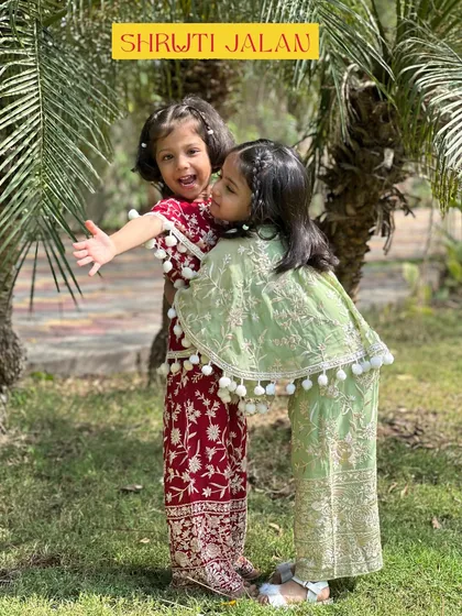 Capturing the pure joy and love between sisters is what inspires me. This candid moment shows two sisters in my coordinated sharara sets, one in festive maroon and the other in fresh green, both detailed with playful pom-pom tassels for extra fun.