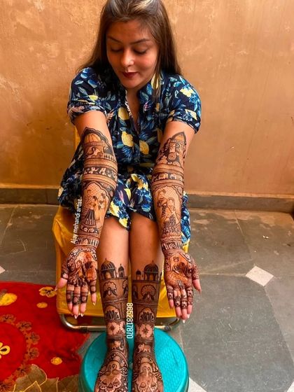A happy bride showing off her full bridal mehndi. The designs on her hands and feet are perfectly coordinated for a stunning wedding look.