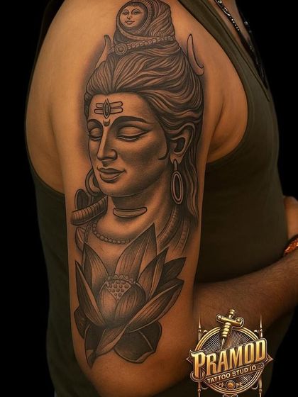 This half-sleeve tattoo features Lord Shiva in a calm state with a blooming lotus below him. The design symbolizes peace, purity, and spiritual awakening, making it a very meaningful piece.