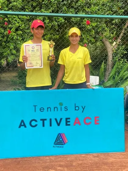 Anahat Mudgil with one of our coaches, standing behind the Tennis by ActiveAce branding after his Under-16 tournament success.