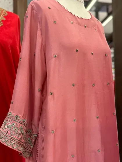 A close-up of a soft pink silk kurta with delicate buti embroidery and detailed work on the cuffs.