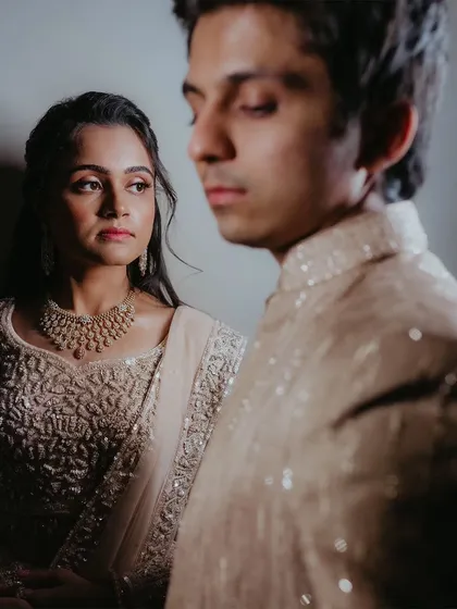 An artistic portrait with a shallow depth of field, focusing on the bride's expression while the groom is softly blurred in the foreground.