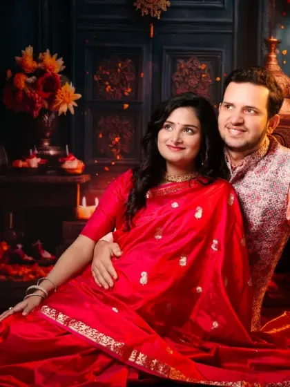 A magical, festive scene for an expecting couple. Dressed in beautiful Indian attire, they are surrounded by the warm, flickering light of numerous candles and diyas.