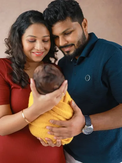 A beautiful perspective showing the parents looking down at their precious baby, swaddled and safe in their hands. It symbolizes their world revolving around this new life.