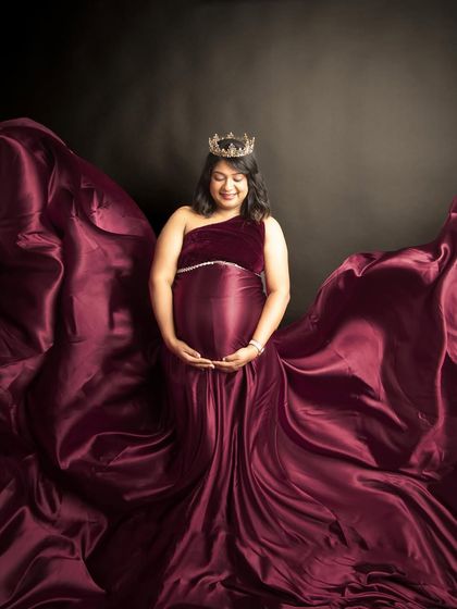 A portrait of pure elegance. The rich wine-red gown, the flowing fabric, and the crown create a regal and timeless look for this beautiful mom-to-be.