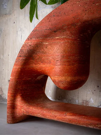 Craftsmanship is in the details. This is a close-up of the Samaveta Console, carved from a single piece of red travertine. The fluid, sculptural lines and the raw, natural texture of the stone come together to create a piece that is both powerful and elegant.