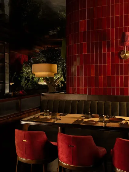 A comfortable booth seating arrangement, where the rich red of the chairs and the glossy tile wall create a warm and inviting corner.