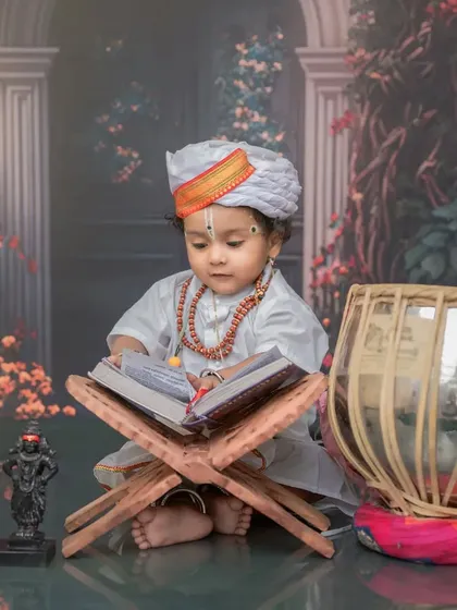 This little Varkari is captured in a moment of quiet contemplation, looking into a holy book. The floral background and soft lighting create a serene and beautiful atmosphere.
