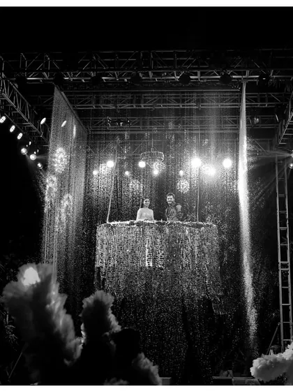 A black and white shot of a high-energy DJ setup for a reception party. The stage is complete with a water curtain and fog effects to create a club-like atmosphere.